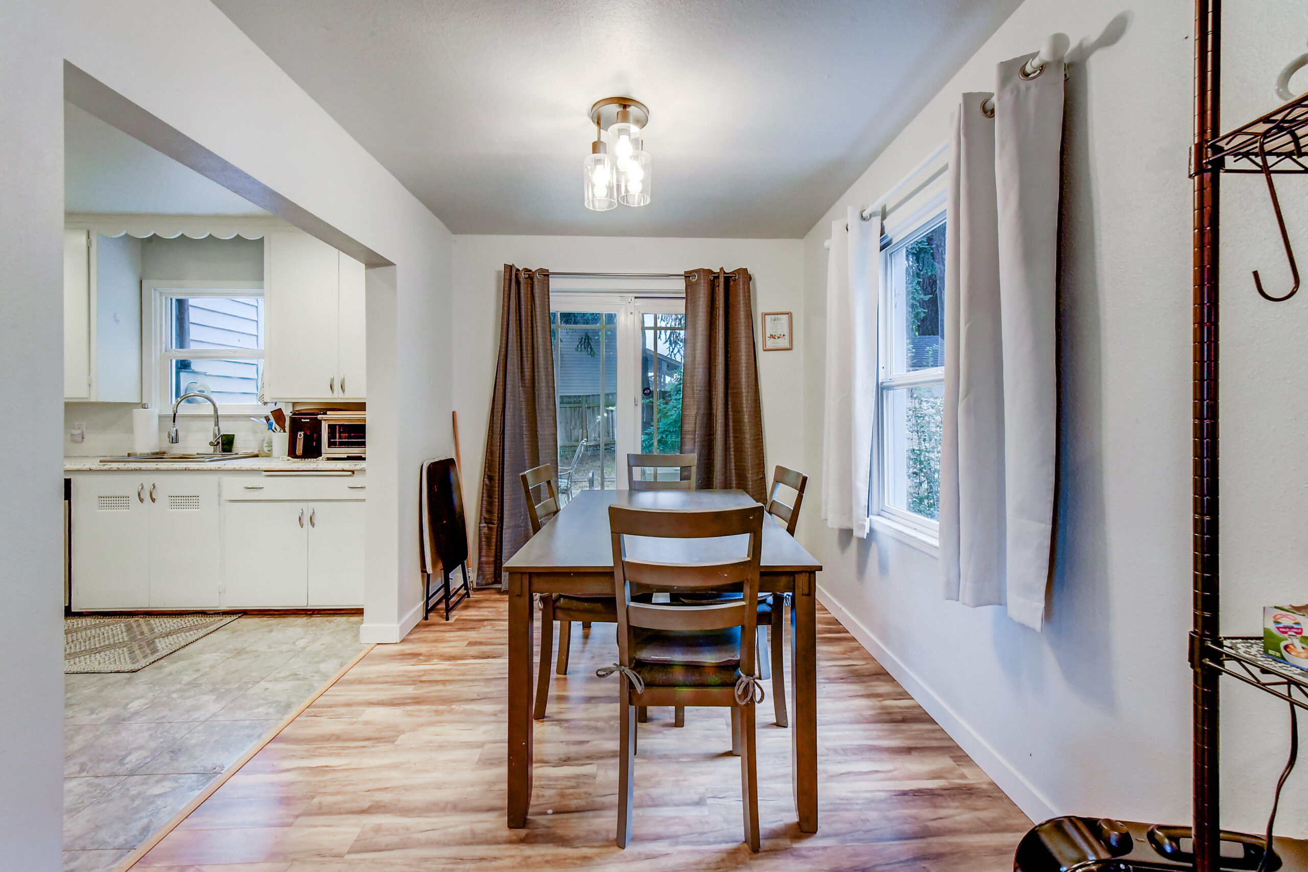 Dining area open to kitchen at the Everett rambler, with wood table and slider to backyard