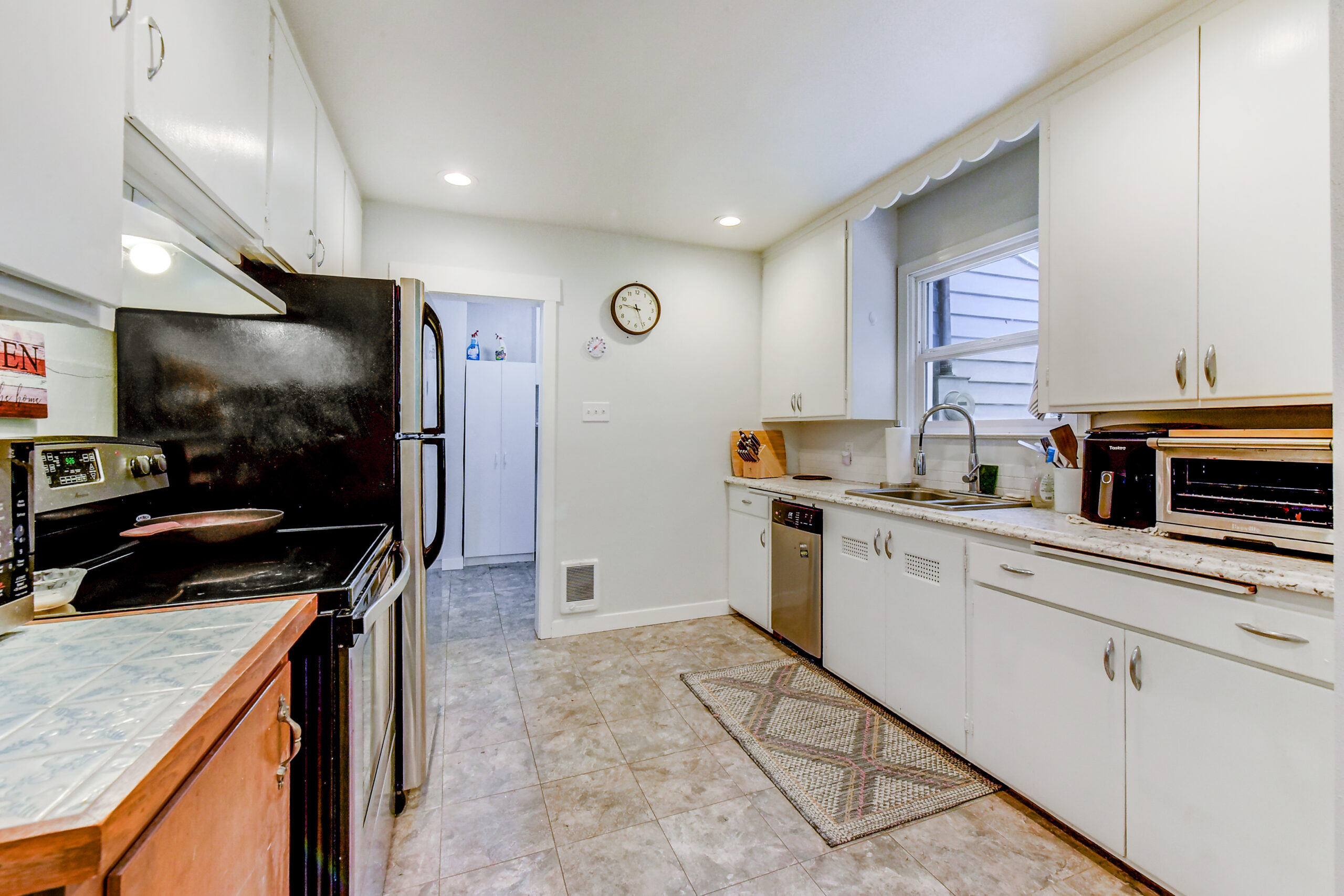 Kitchen with white cabinets, tile floor, and stainless appliances at the Everett rambler on Madison St