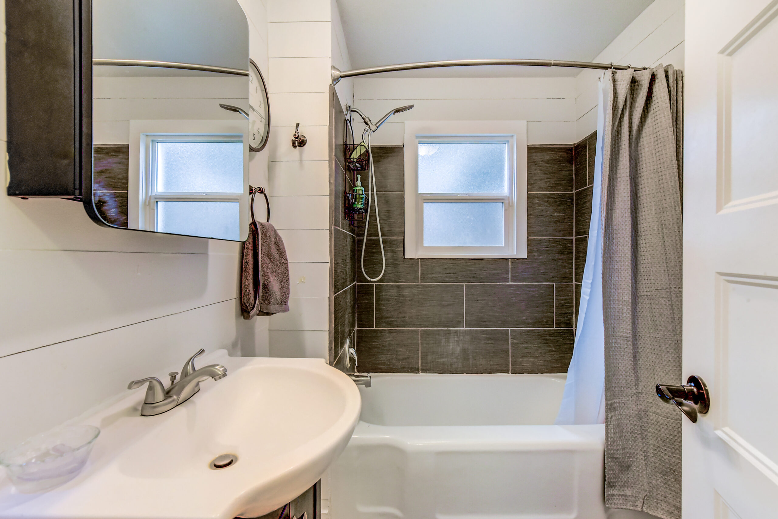 Bathroom with tiled tub-shower, sink, and mirror at the Everett rambler on Madison St