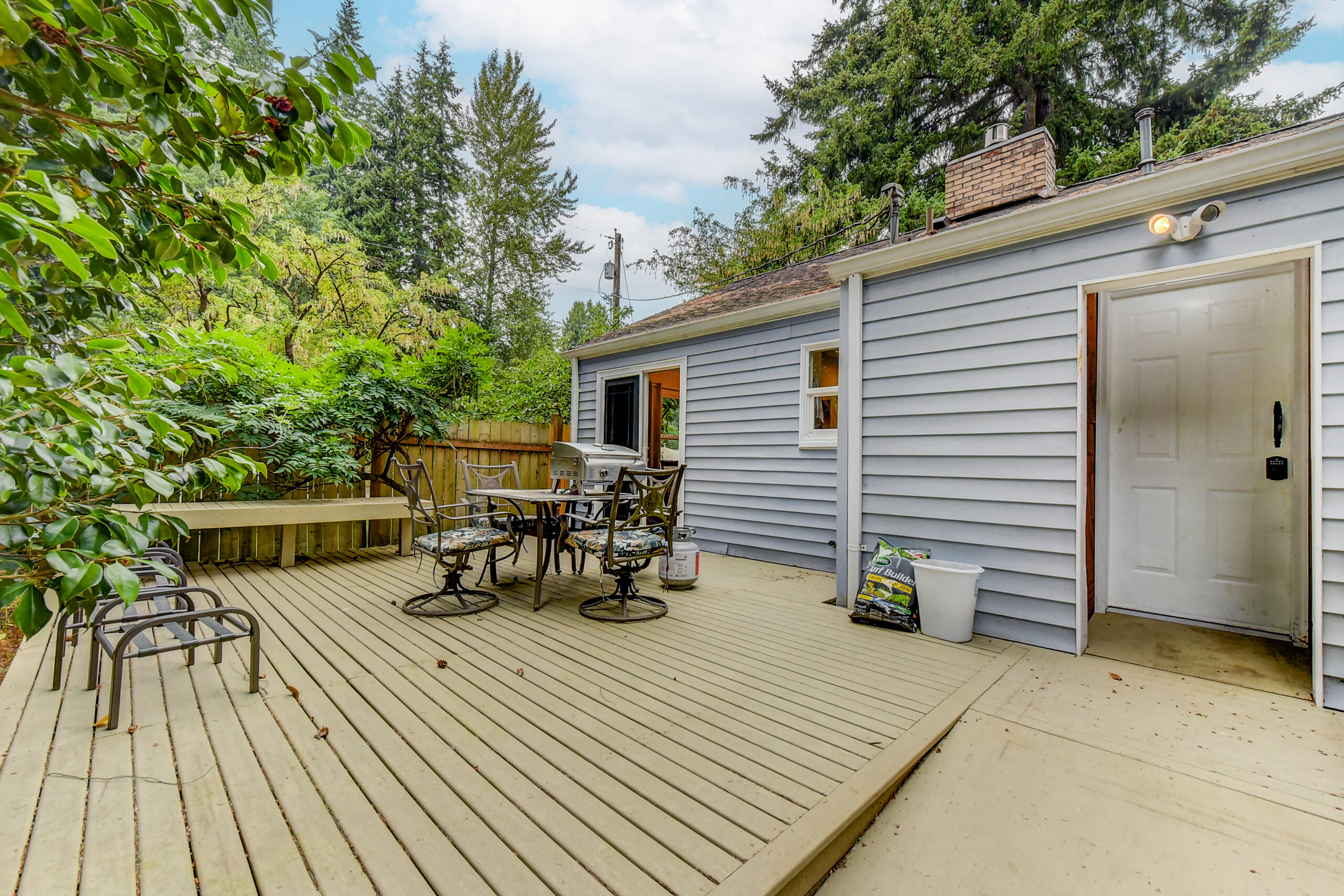 Back deck with patio seating and grill at the Everett rambler, surrounded by mature trees