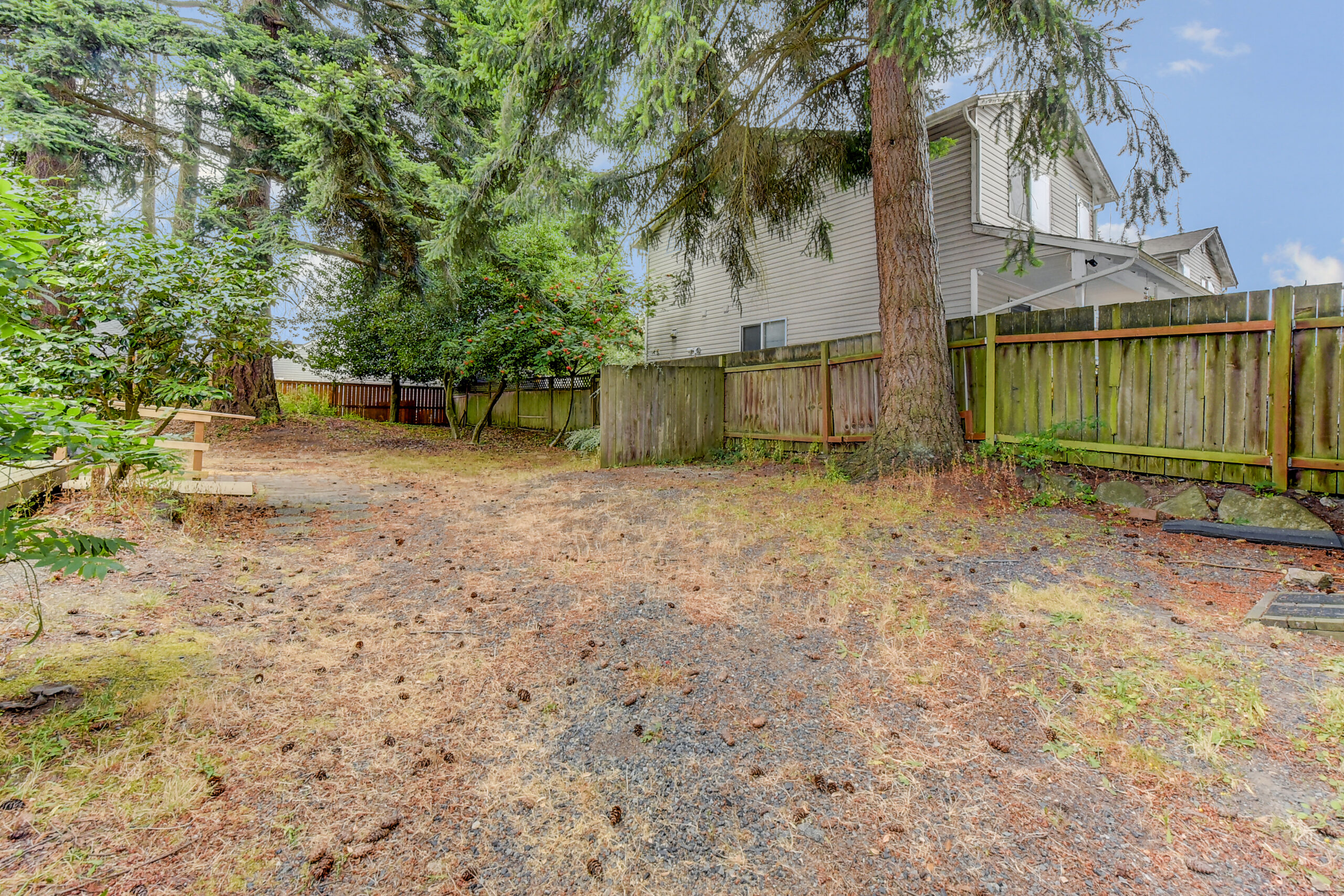 Fenced backyard with mature trees at the Everett rambler, quarter-acre lot with fencing visible