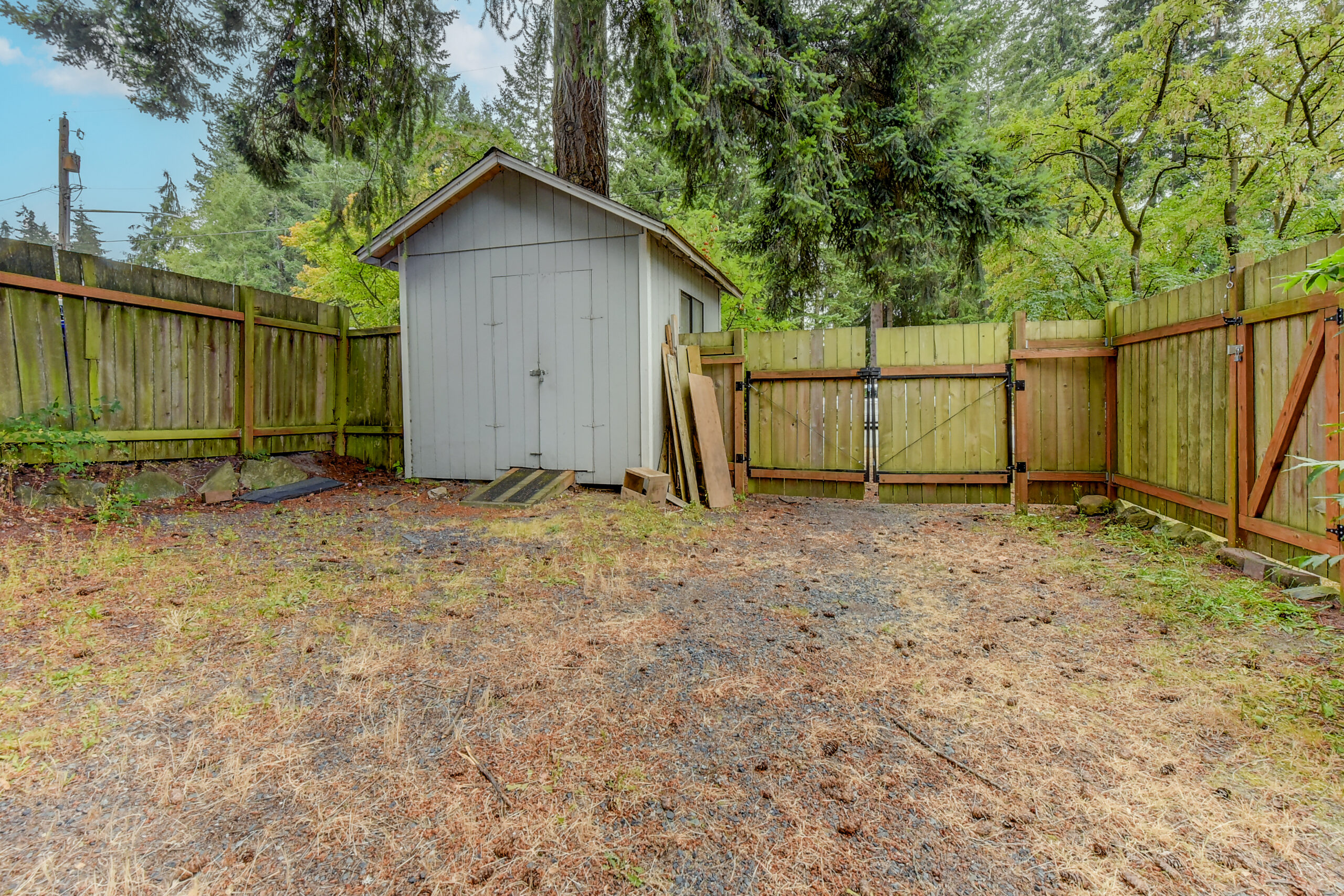 Fenced backyard with garden shed and gravel area at the Everett rambler on Madison St