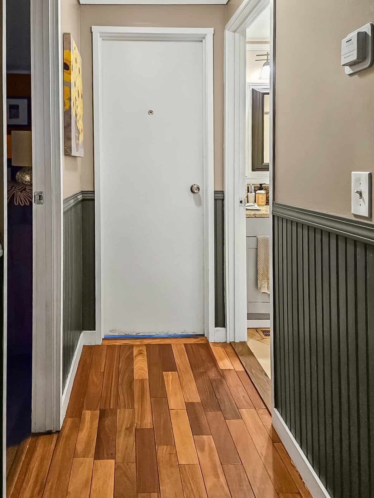 Hallway with wood flooring and wainscoting leading to bathroom, Concrete home interior
