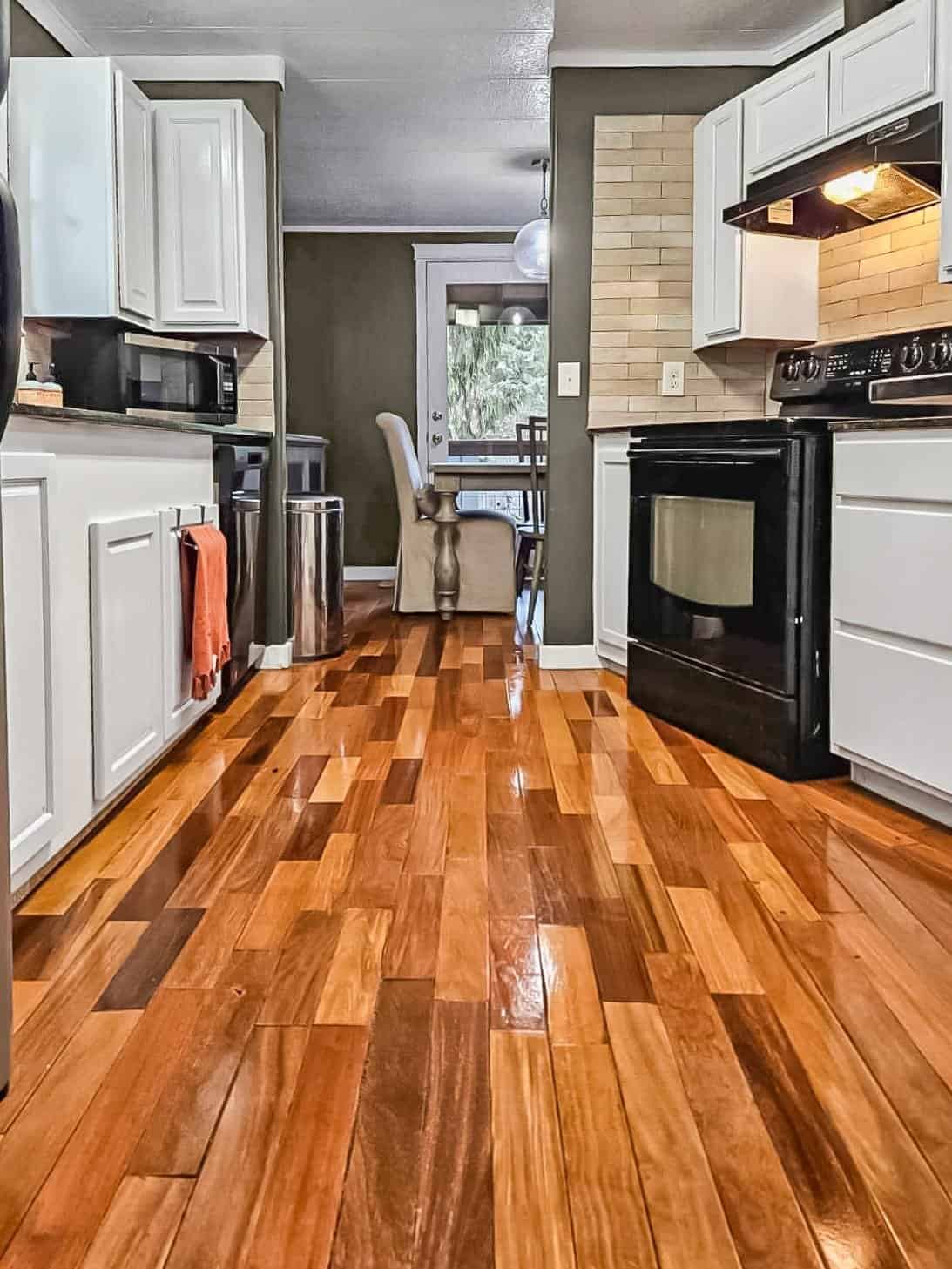 Kitchen with white cabinets, black stove and glossy hardwood floors, Concrete home