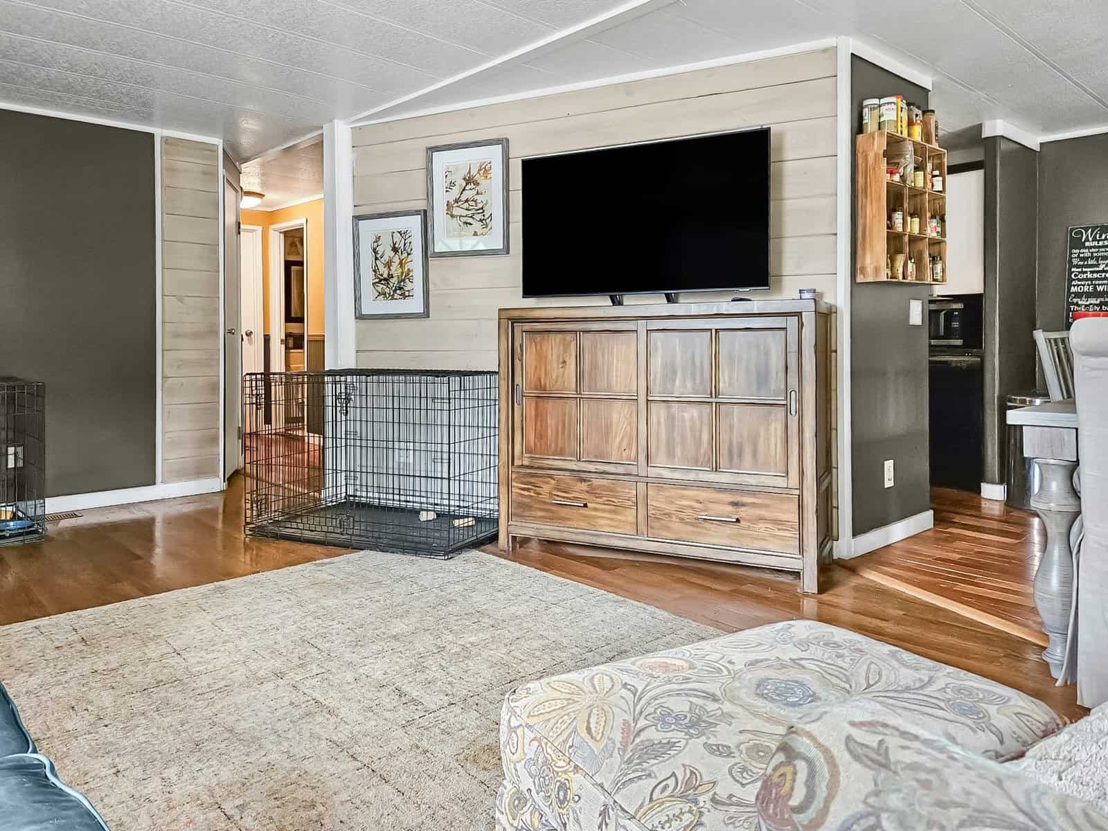Living room with mounted TV, wood entertainment cabinet, and hardwood floors in the Concrete, WA home