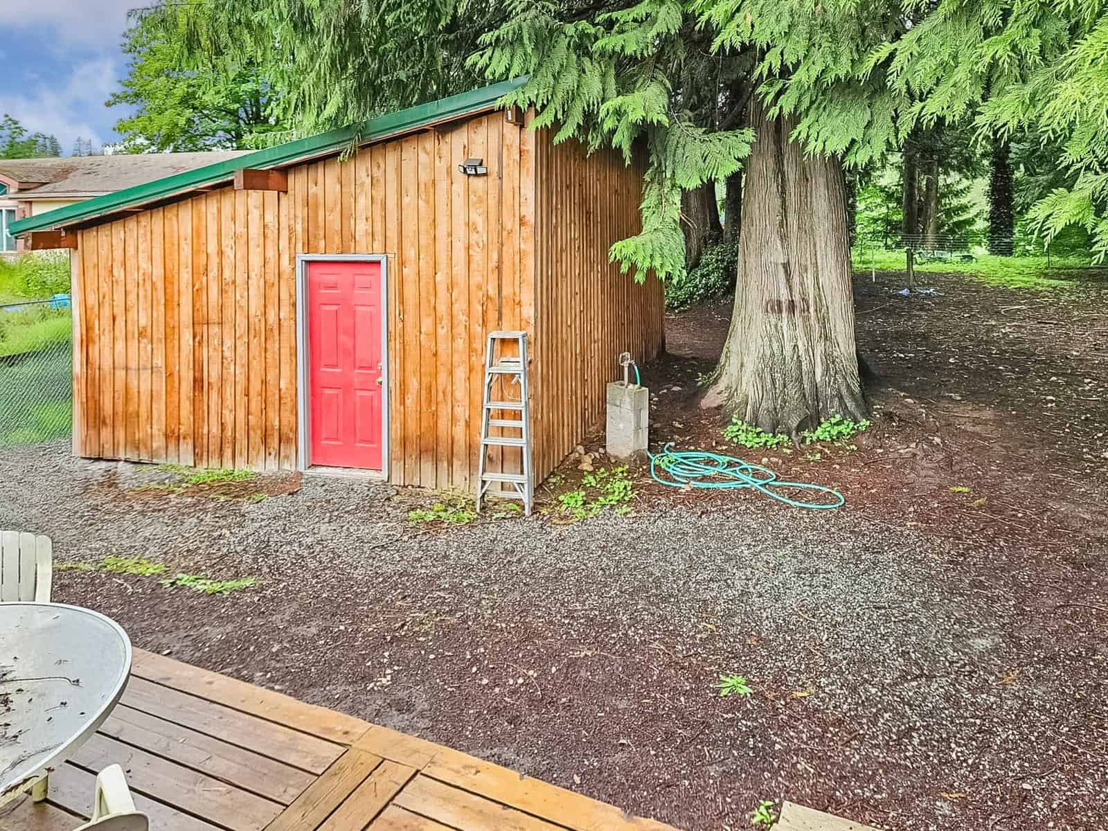 Wooden outbuilding with red door and outdoor spigot on the Concrete, WA property lot