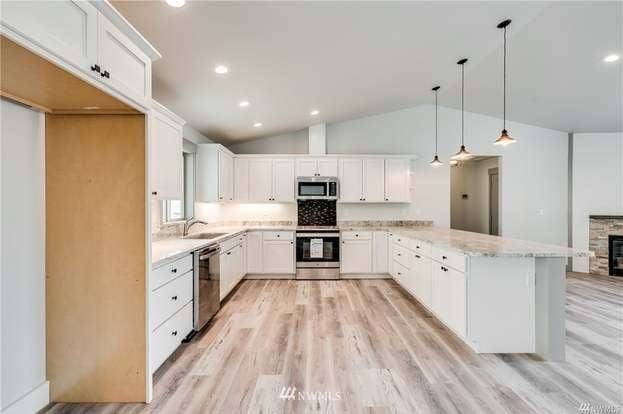 Kitchen with white cabinetry, island seating, and vaulted ceiling in Entiat rambler home