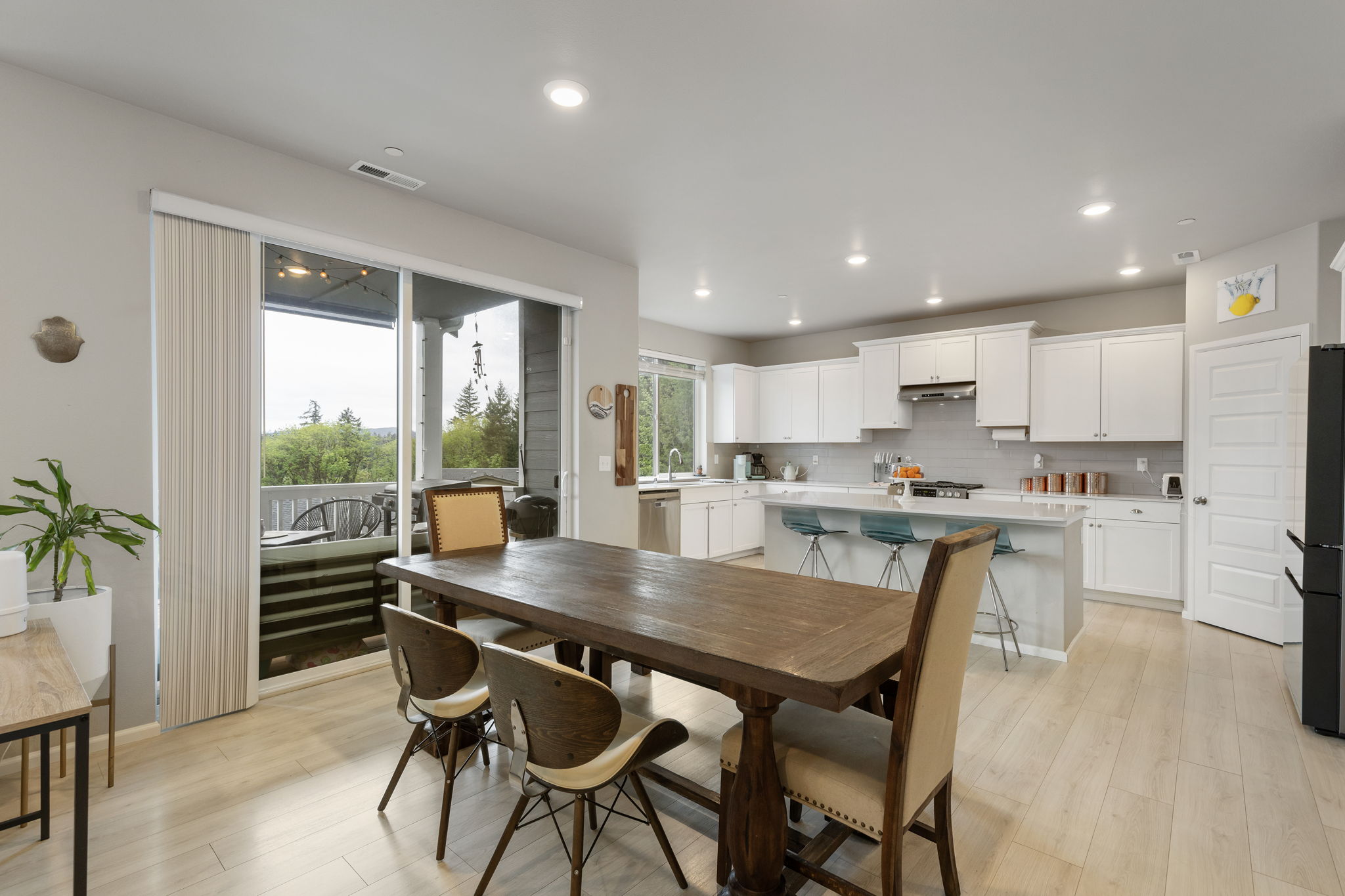 Open kitchen and dining area with white cabinetry, island seating, and deck access in this Port Orchard rent-to-own home