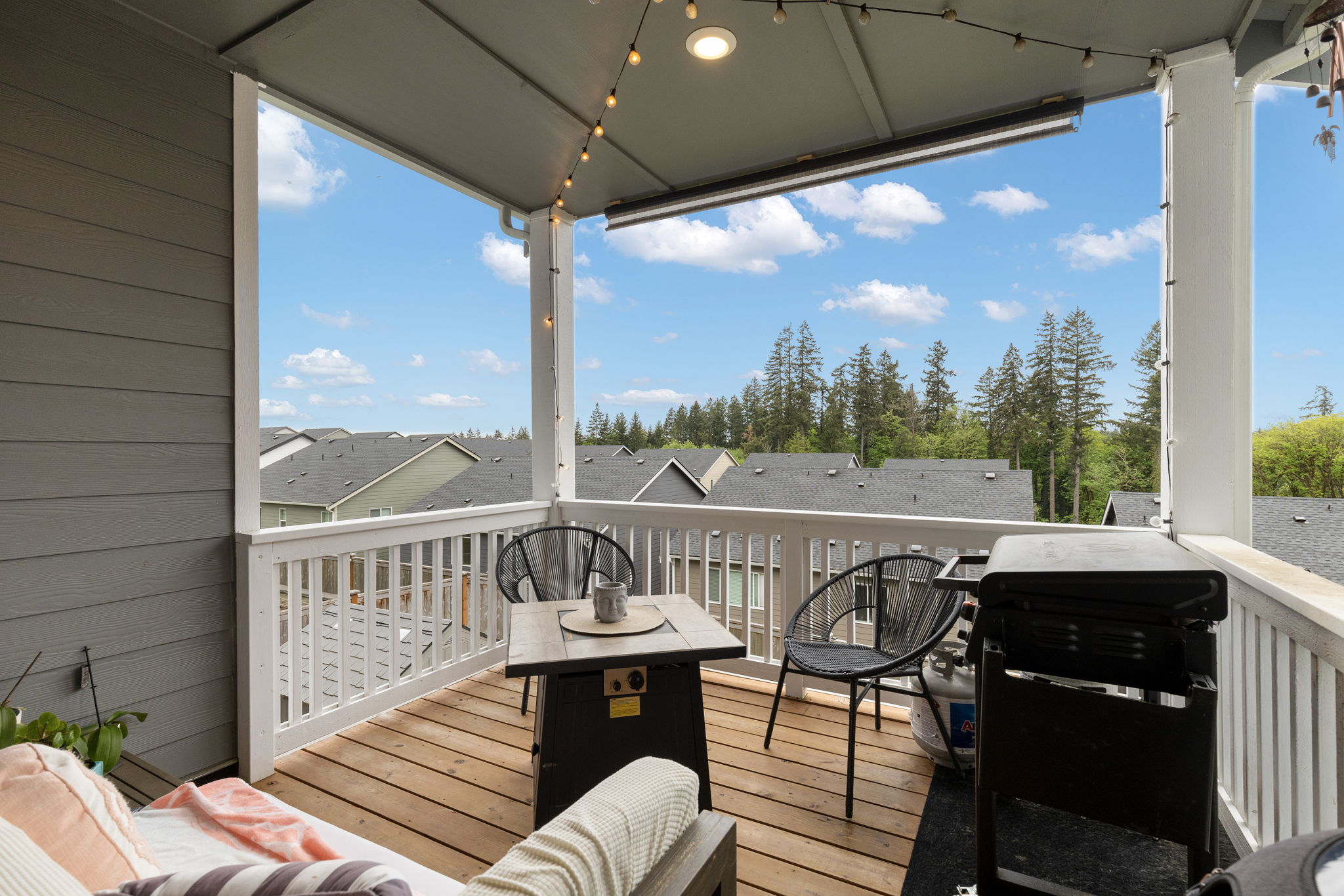 Covered deck with seating, grill, and treetop views at the Port Orchard rent-to-own home