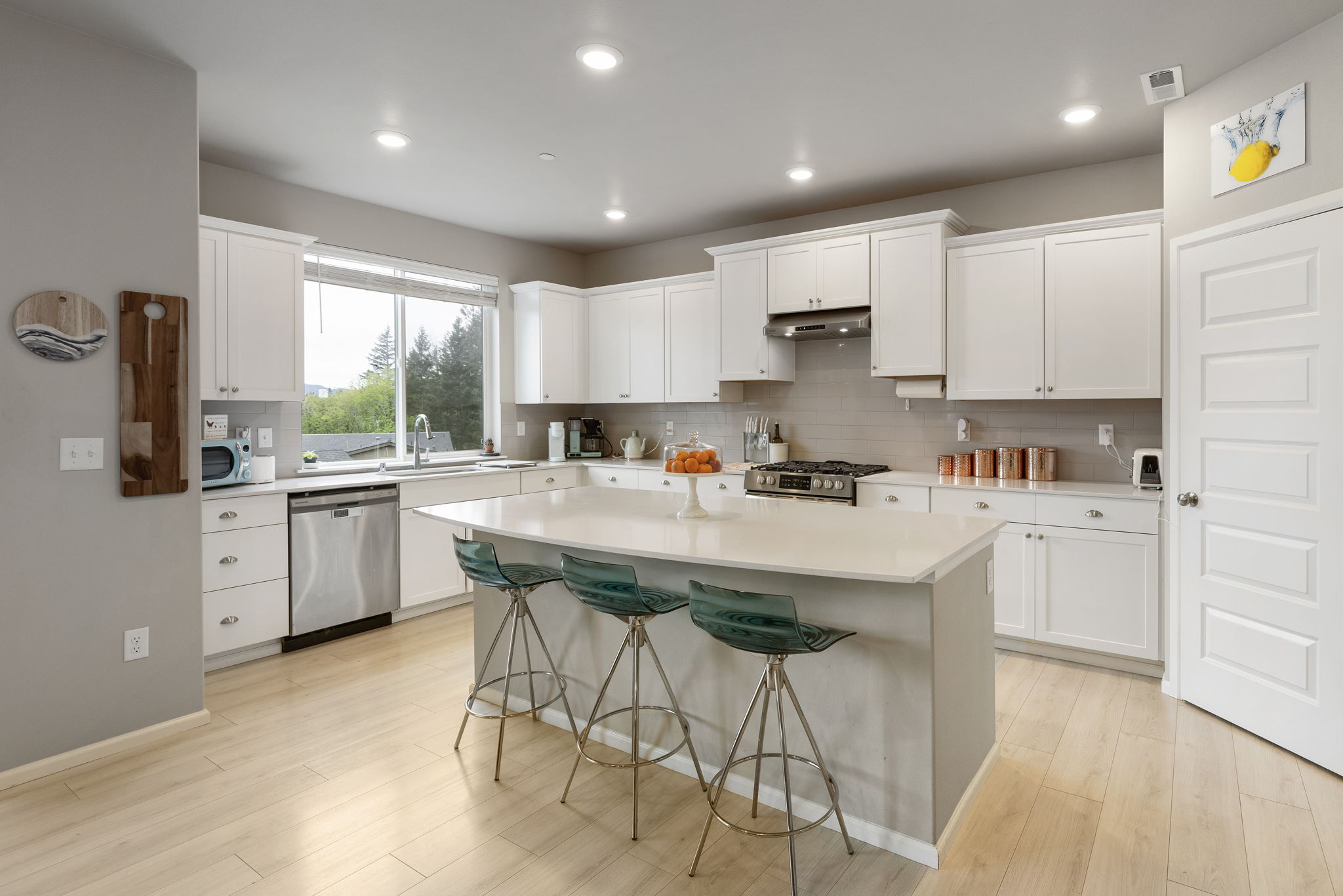 Kitchen with white cabinetry, island seating for three, and stainless appliances at the Port Orchard rent-to-own home