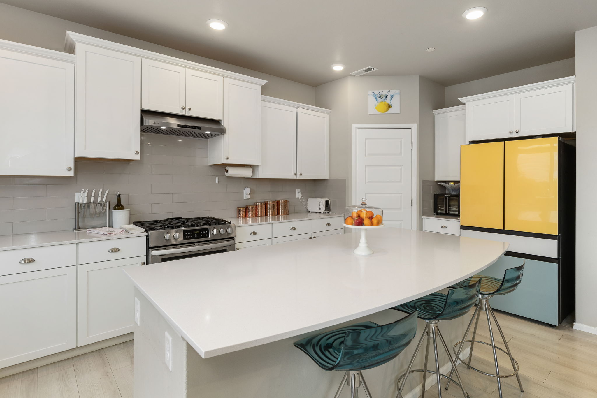 Kitchen with white cabinetry, island seating, and gas range in the Port Orchard rent-to-own home