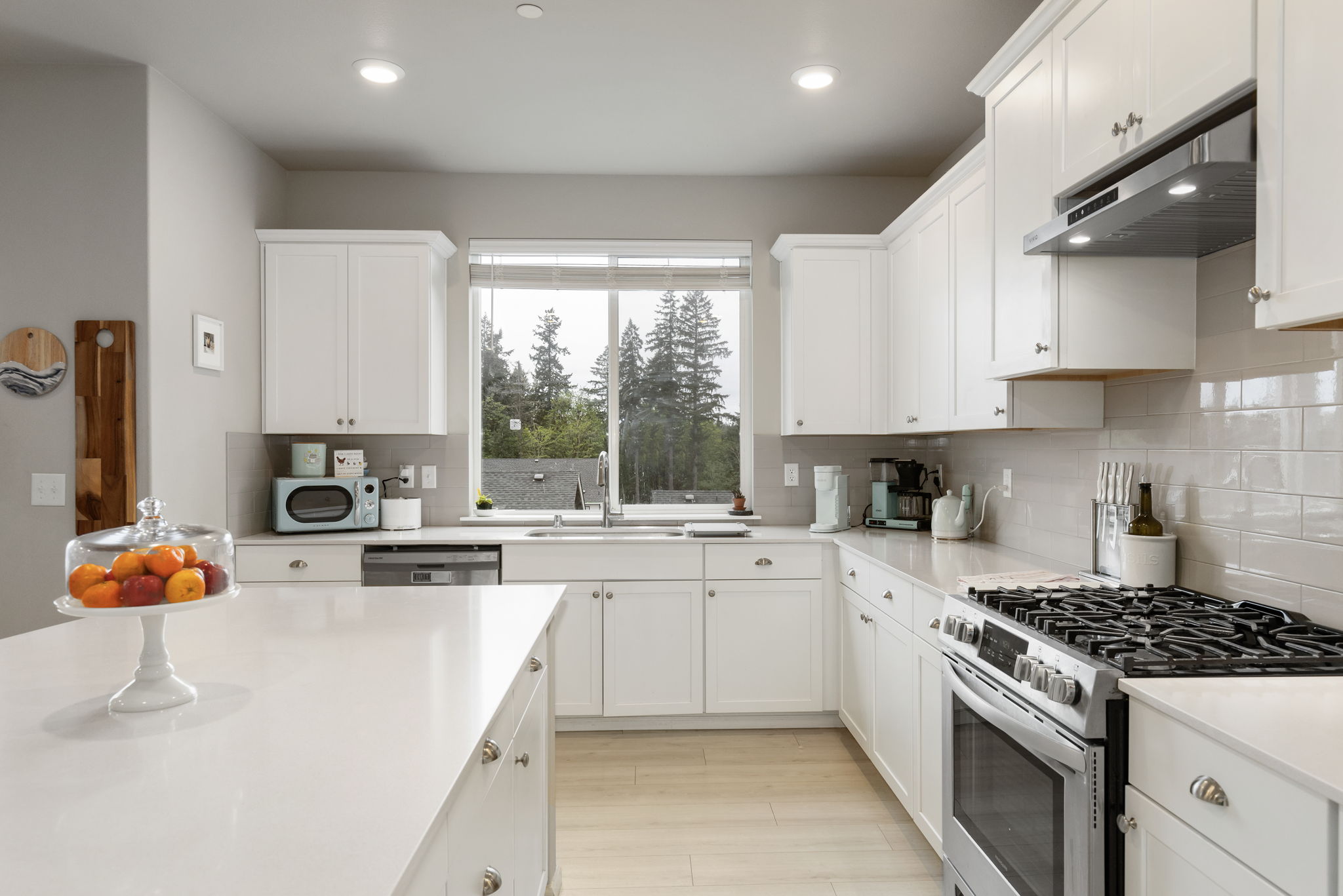 Kitchen with white cabinetry, gas range, and quartz counters in the Port Orchard rent-to-own home