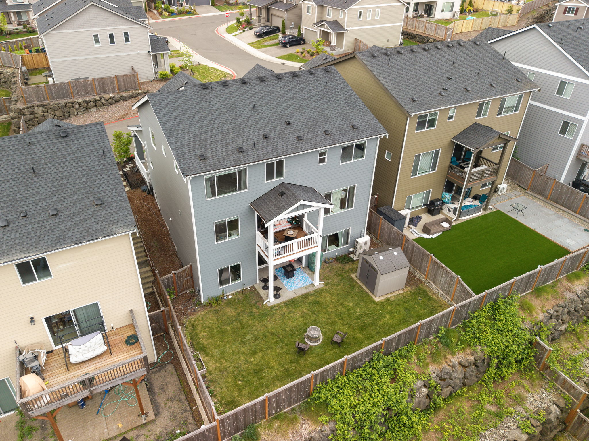 Aerial view of the Port Orchard home's back exterior, deck, and fenced backyard with storage shed
