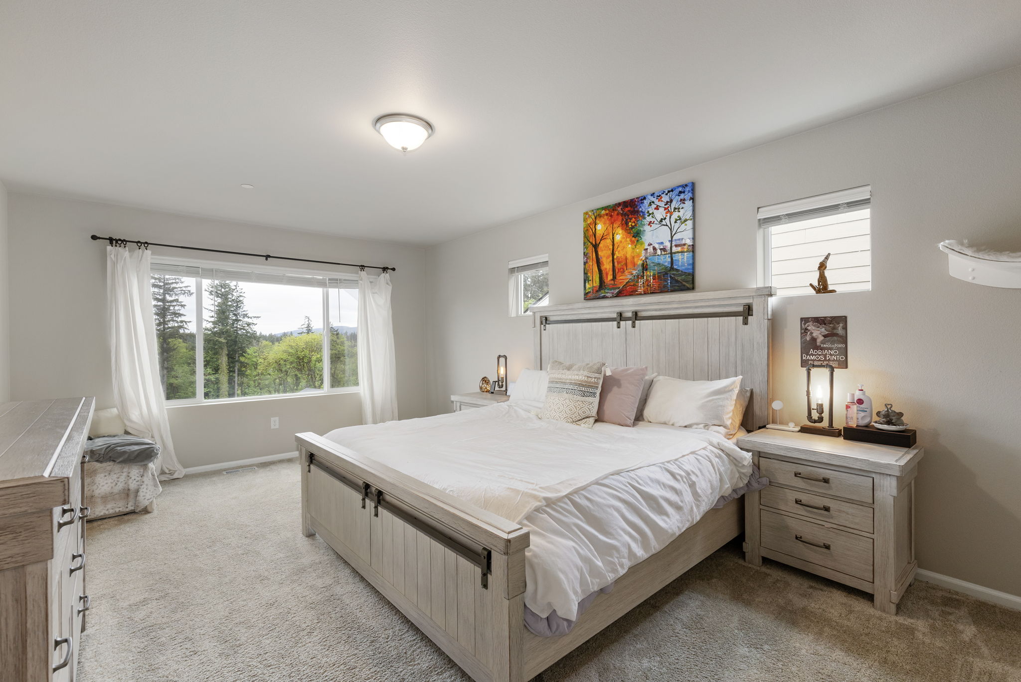 Primary bedroom with wooden barn-door bed frame and wooded view, 962 Thrush Ct SE Port Orchard home