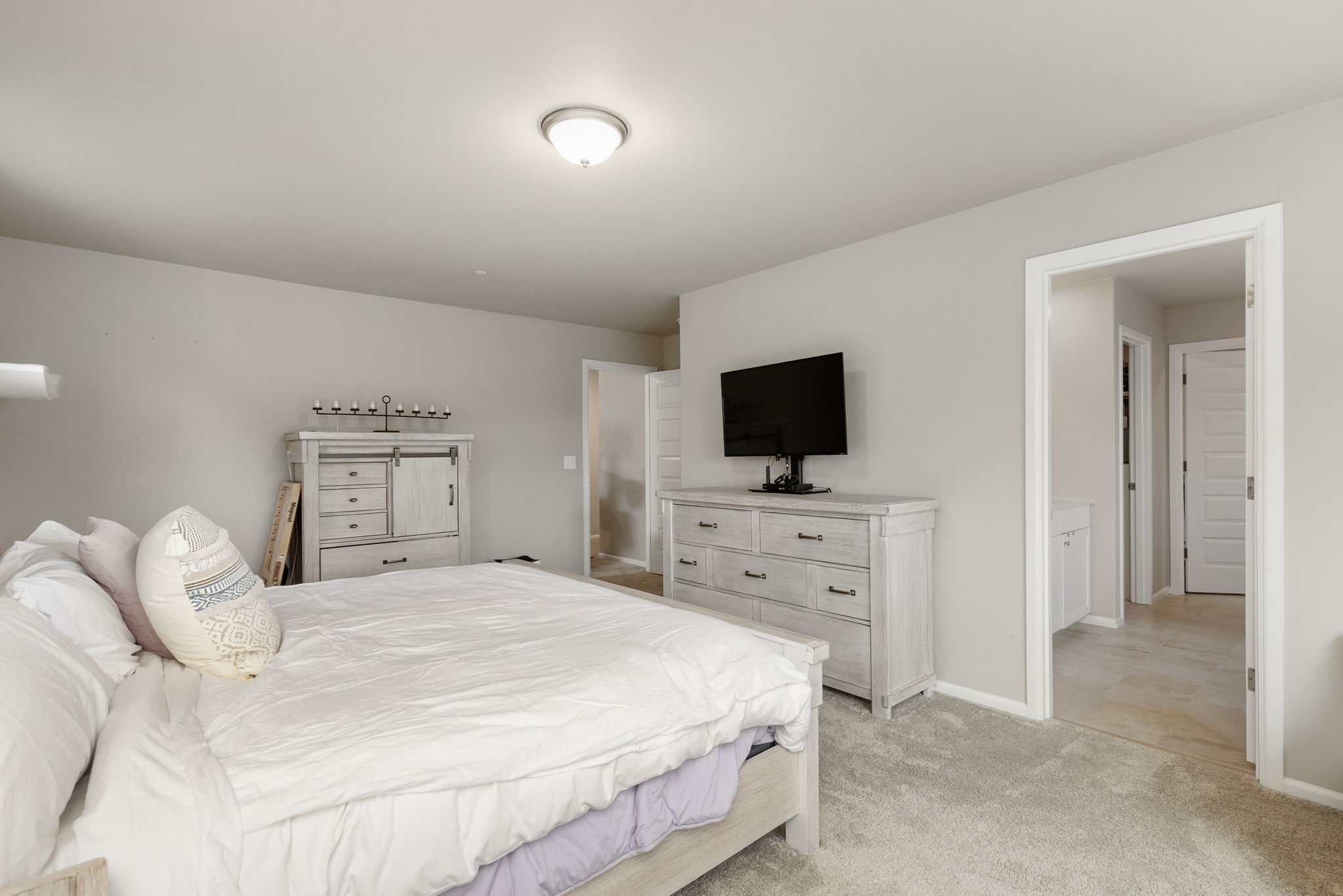 Primary bedroom with dresser, mounted TV, and en-suite bathroom access in this Port Orchard home
