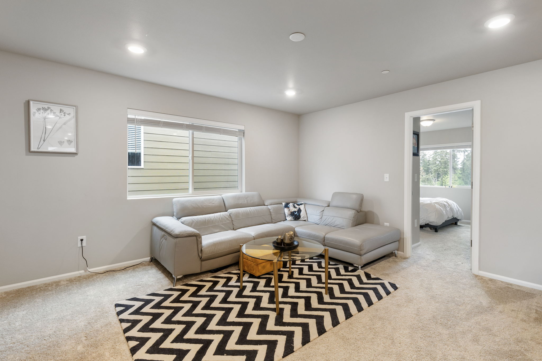 Basement suite living area with sectional sofa, opening to bedroom, in the Port Orchard rent-to-own home