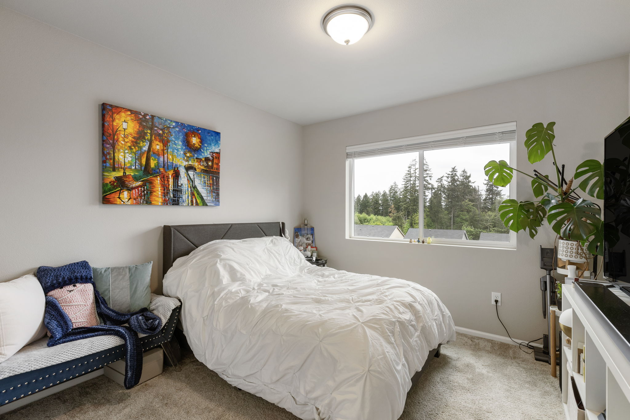 Bedroom with tree-view window at the Port Orchard rent-to-own home, carpeted floor and wall art
