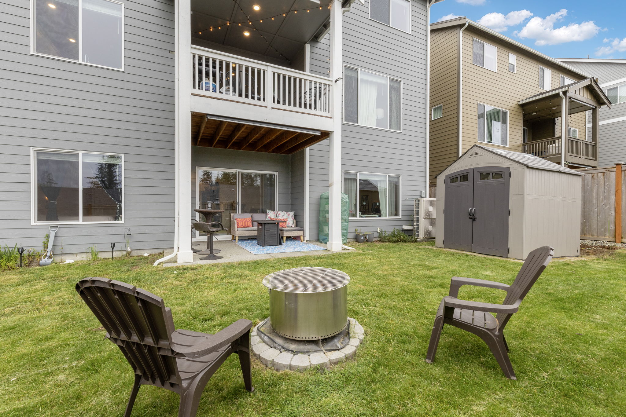 Backyard with fire pit, patio seating, and storage shed at the Port Orchard rent-to-own home