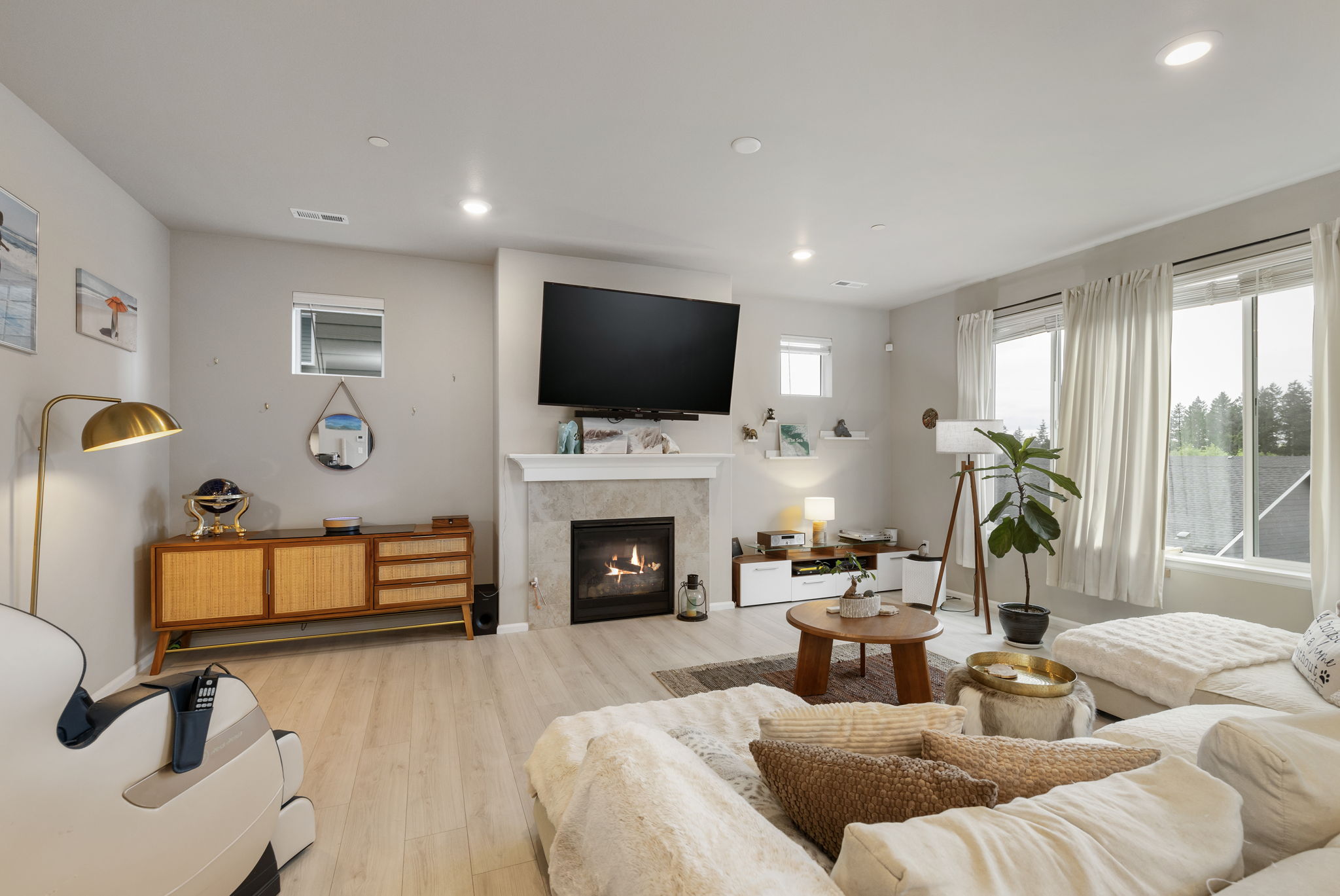 Living room with gas fireplace, mounted TV, and large windows in the Port Orchard rent-to-own home