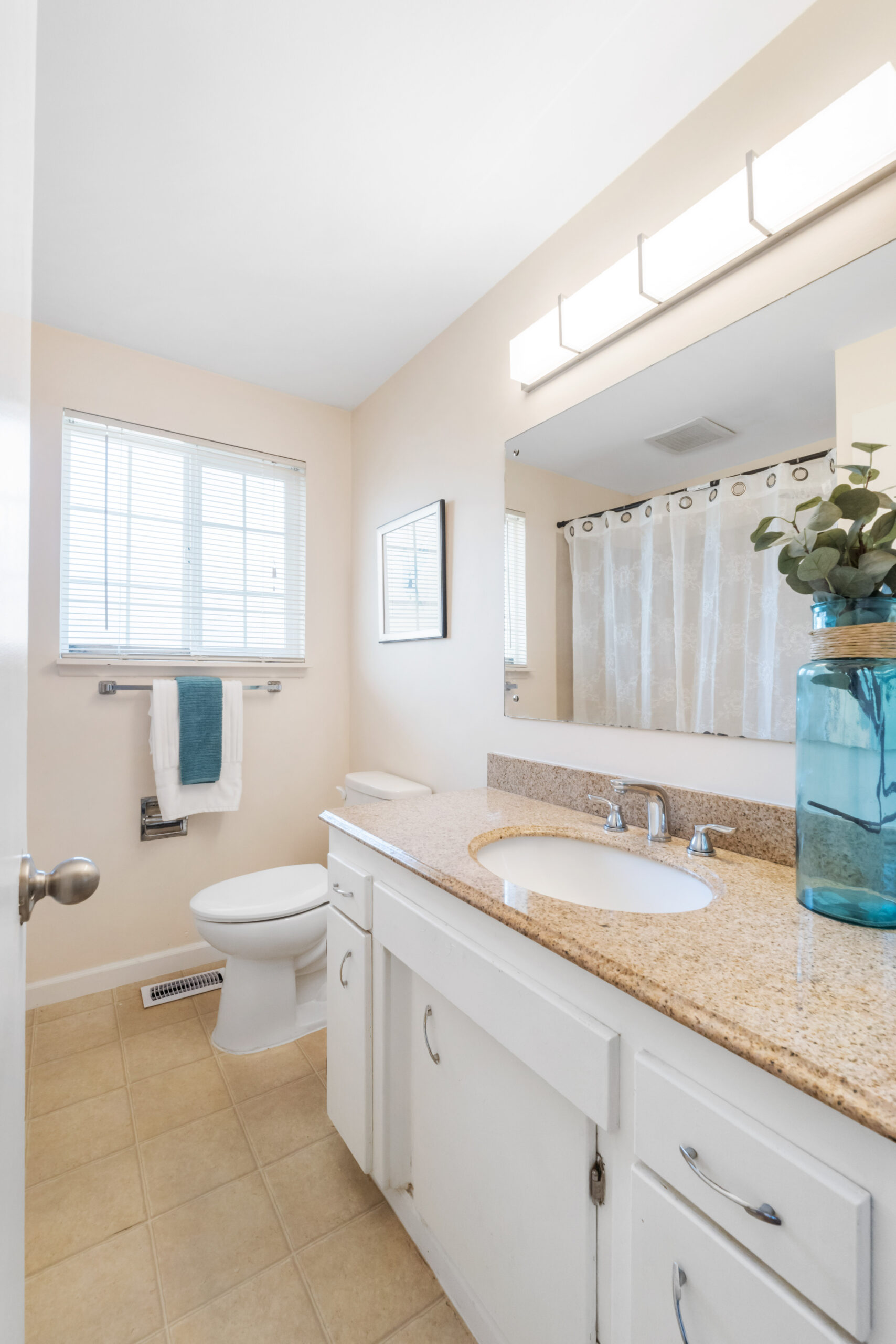 Full bathroom with granite vanity, toilet, and shower at the Auburn duplex listing