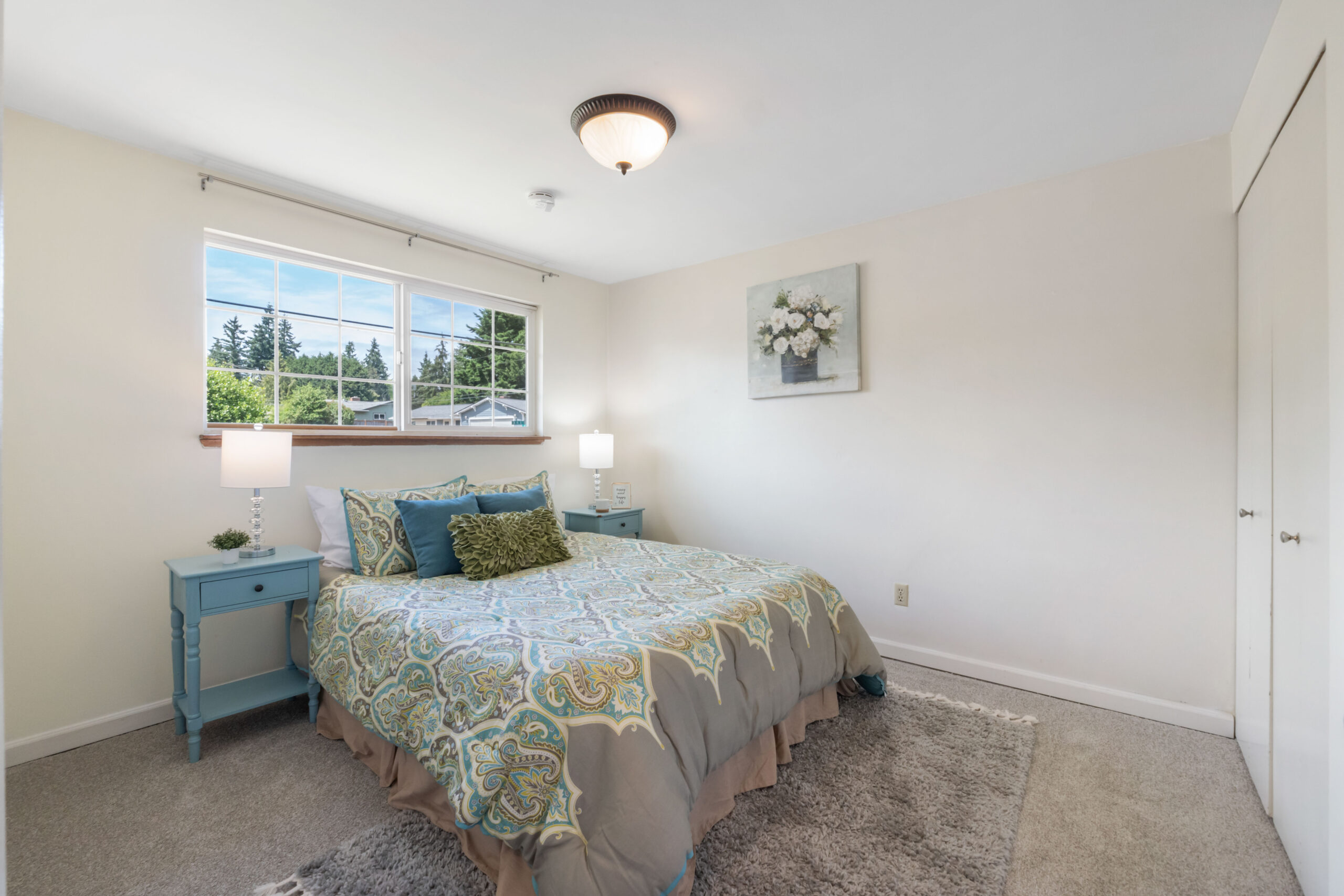 Upstairs bedroom with carpet, closet, and window view of trees in this Auburn duplex unit