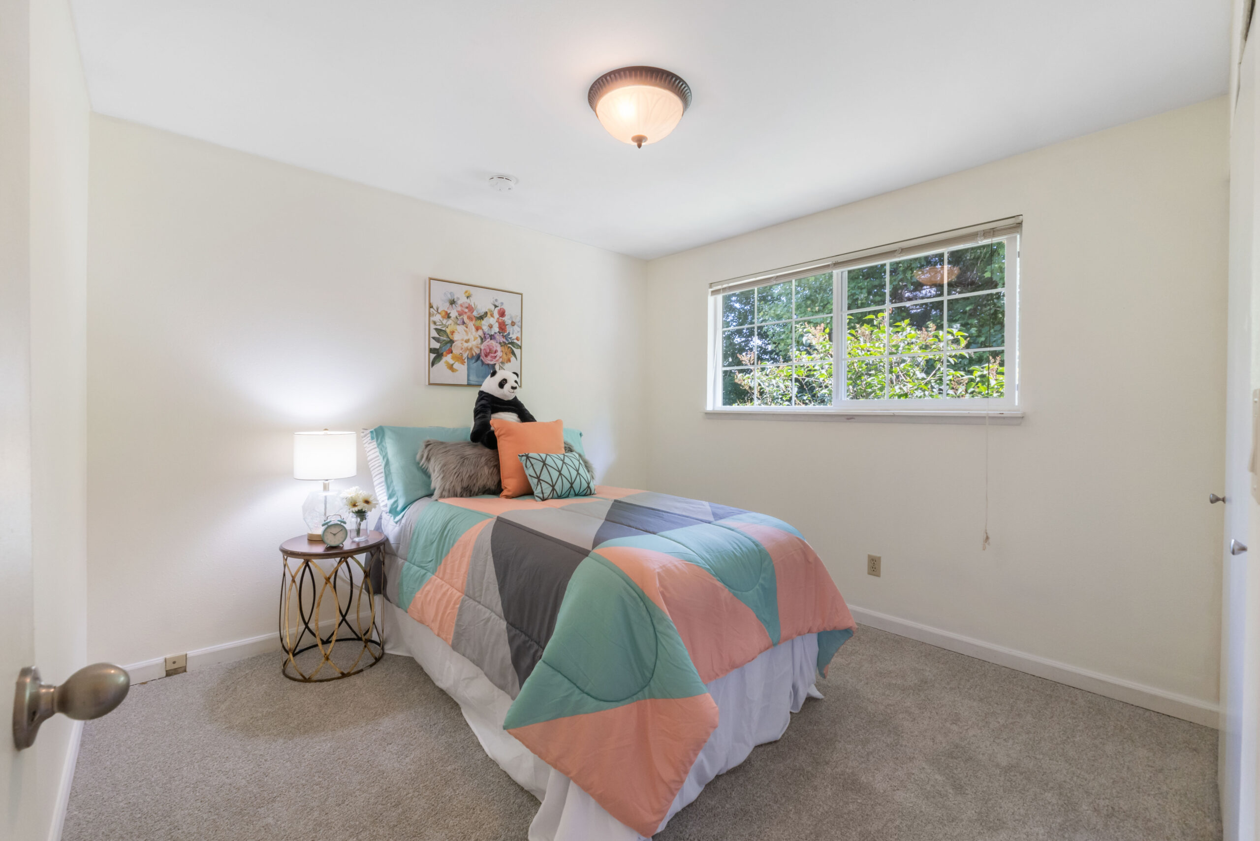 Carpeted bedroom with window view of trees in the Auburn duplex's upstairs unit
