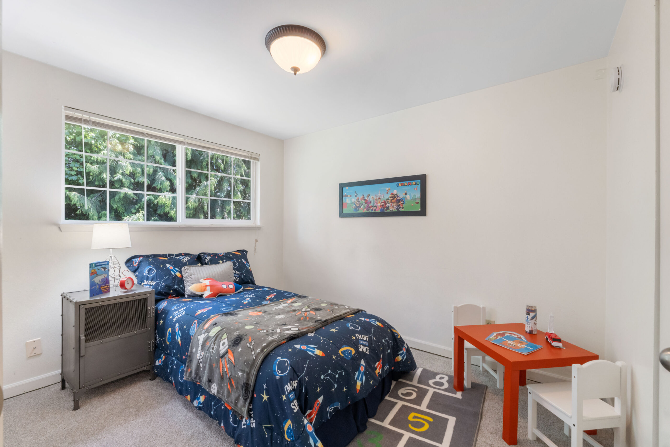 Kids' bedroom with space-themed bedding and play table in the Auburn duplex upstairs unit