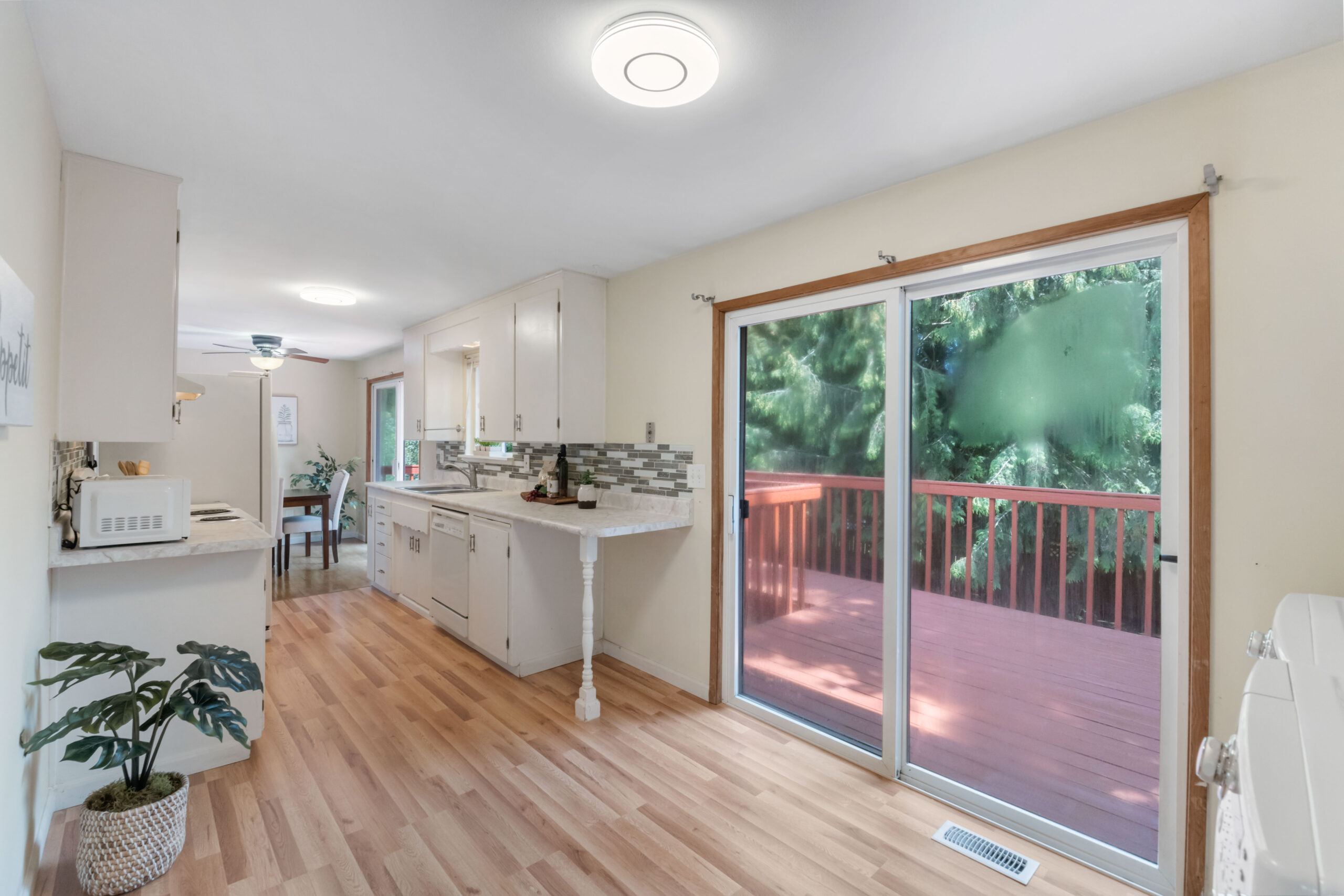 Kitchen with white cabinets, sliding glass door to large deck, in this Auburn duplex unit