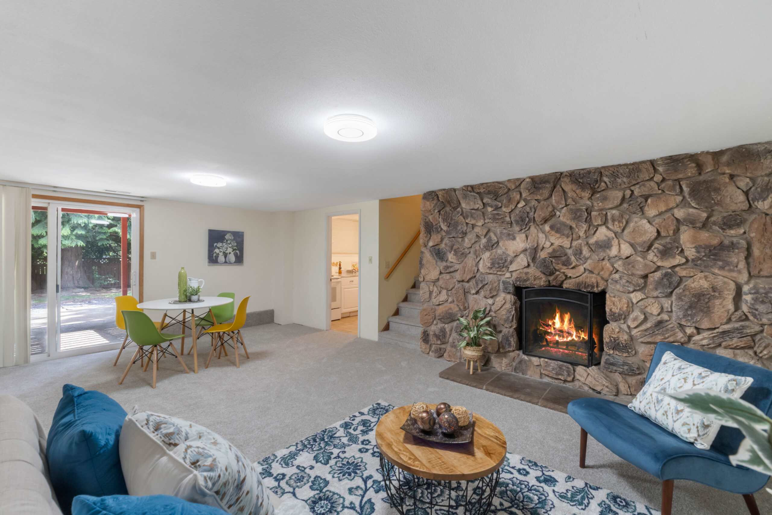 Living room with stone fireplace, dining nook, and stairway in this Auburn duplex unit
