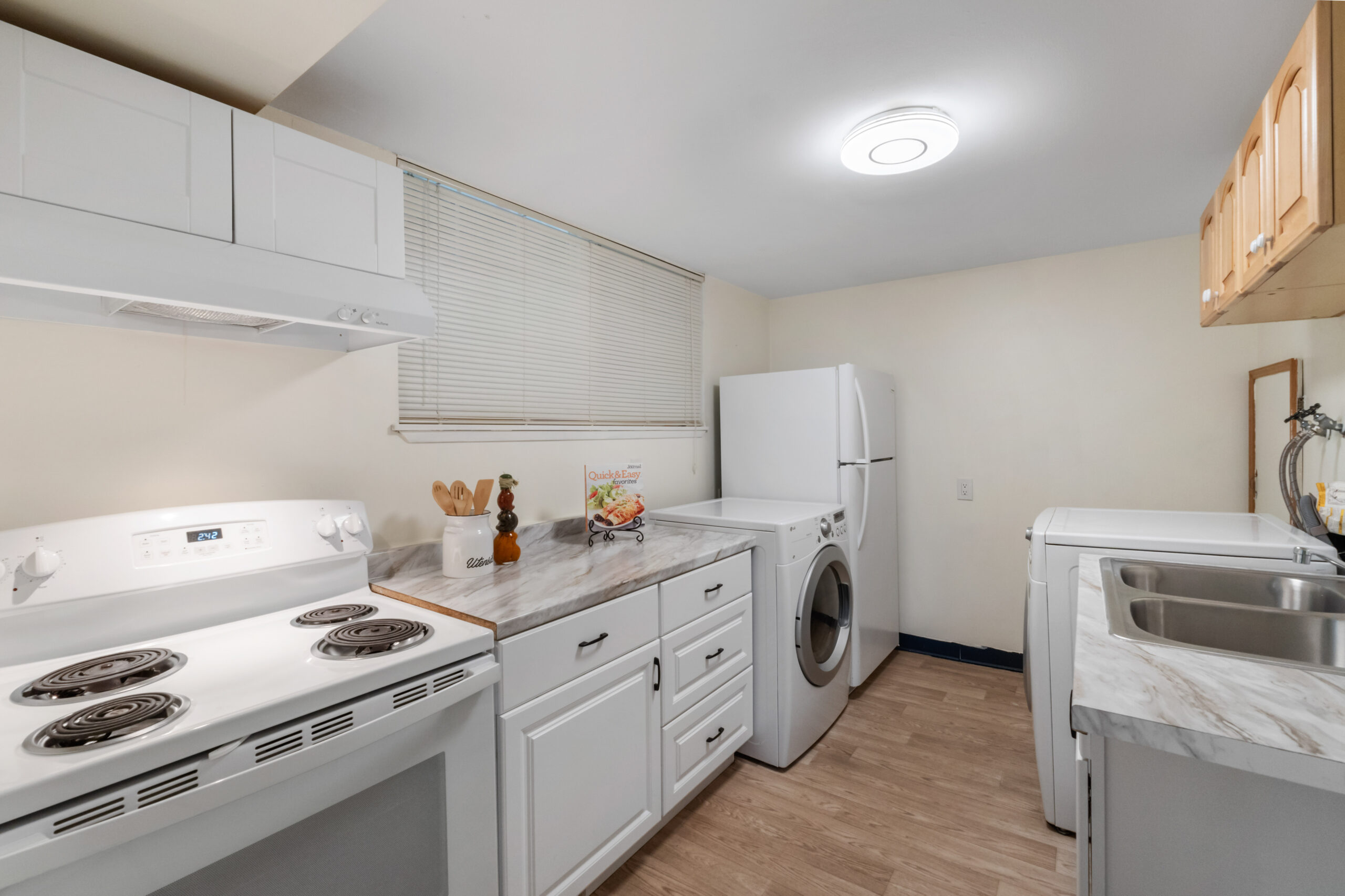 Downstairs unit kitchen with in-unit washer/dryer, fridge and stove at the Auburn duplex
