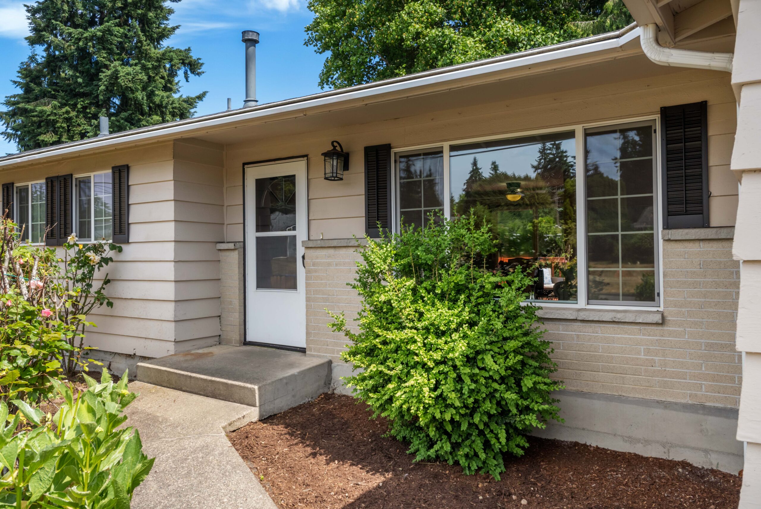 Front entrance walkway and door of the Auburn duplex, with landscaped shrubs and large windows