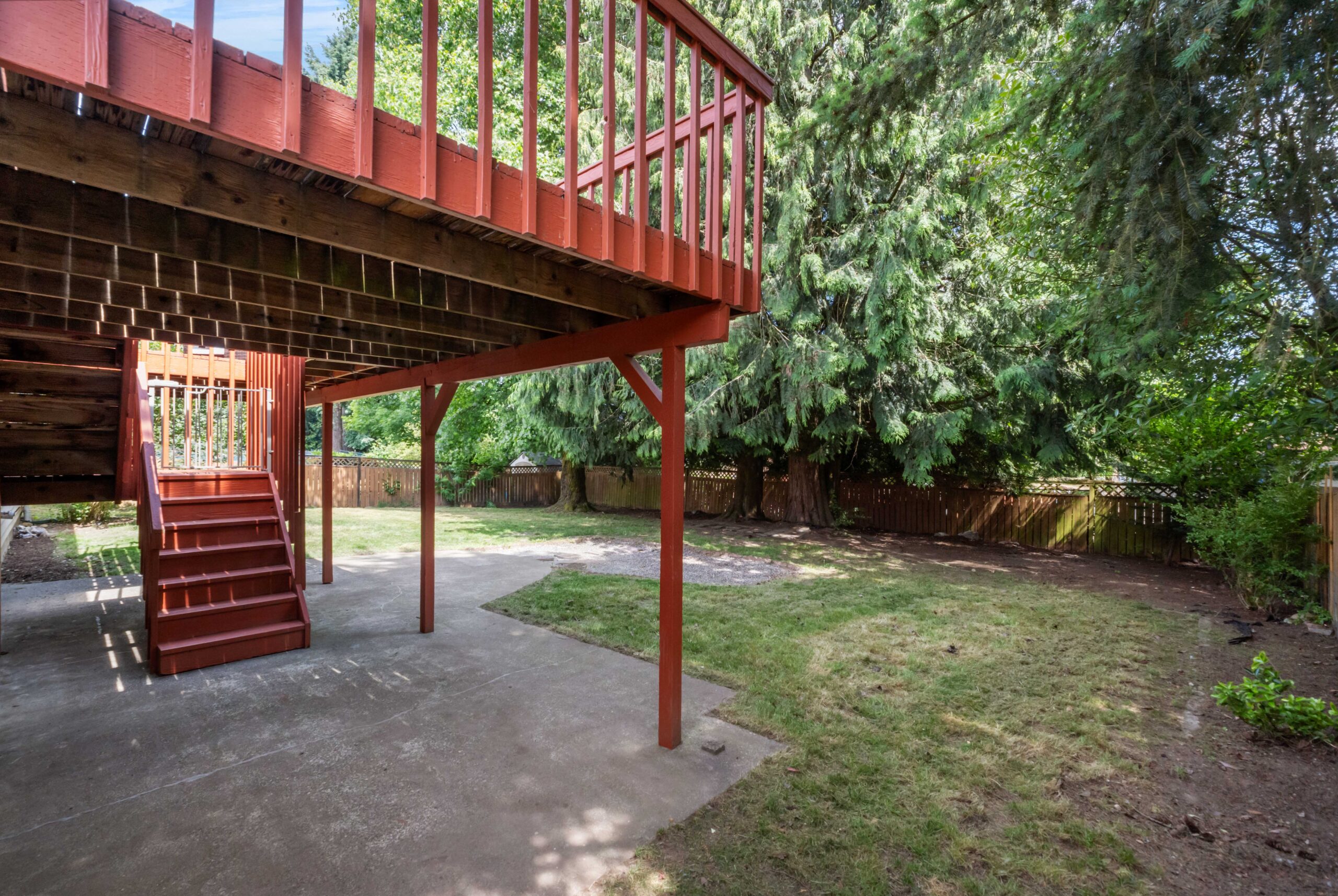 Fenced backyard with covered patio, deck above, and stairs at the Auburn duplex on 38th Pl S
