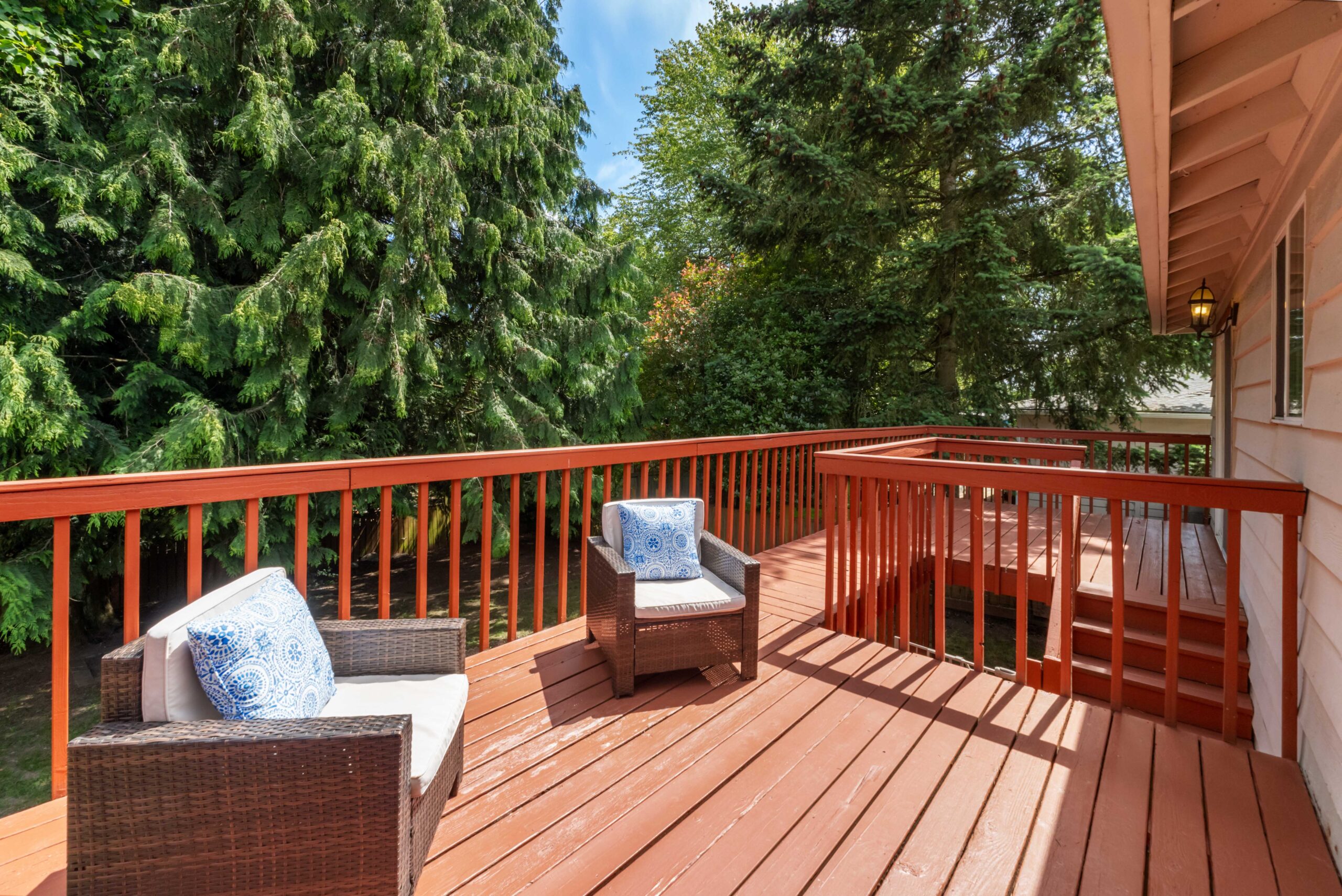 Large wood deck with wicker seating overlooking trees at the Auburn duplex home