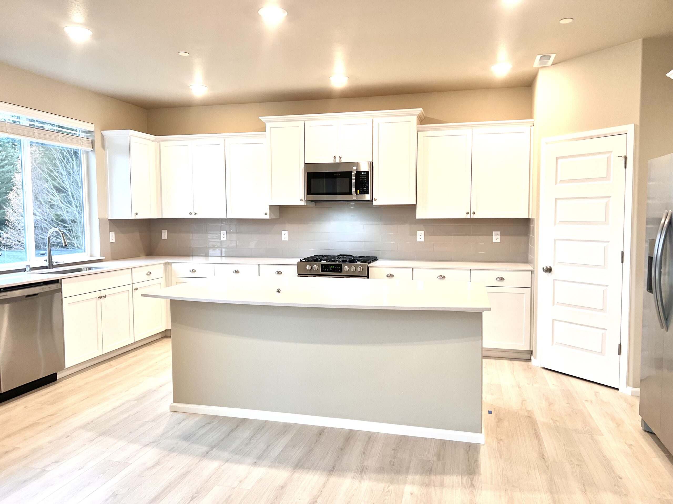 Kitchen with white cabinets, island, and stainless appliances in the Port Orchard rent-to-own home