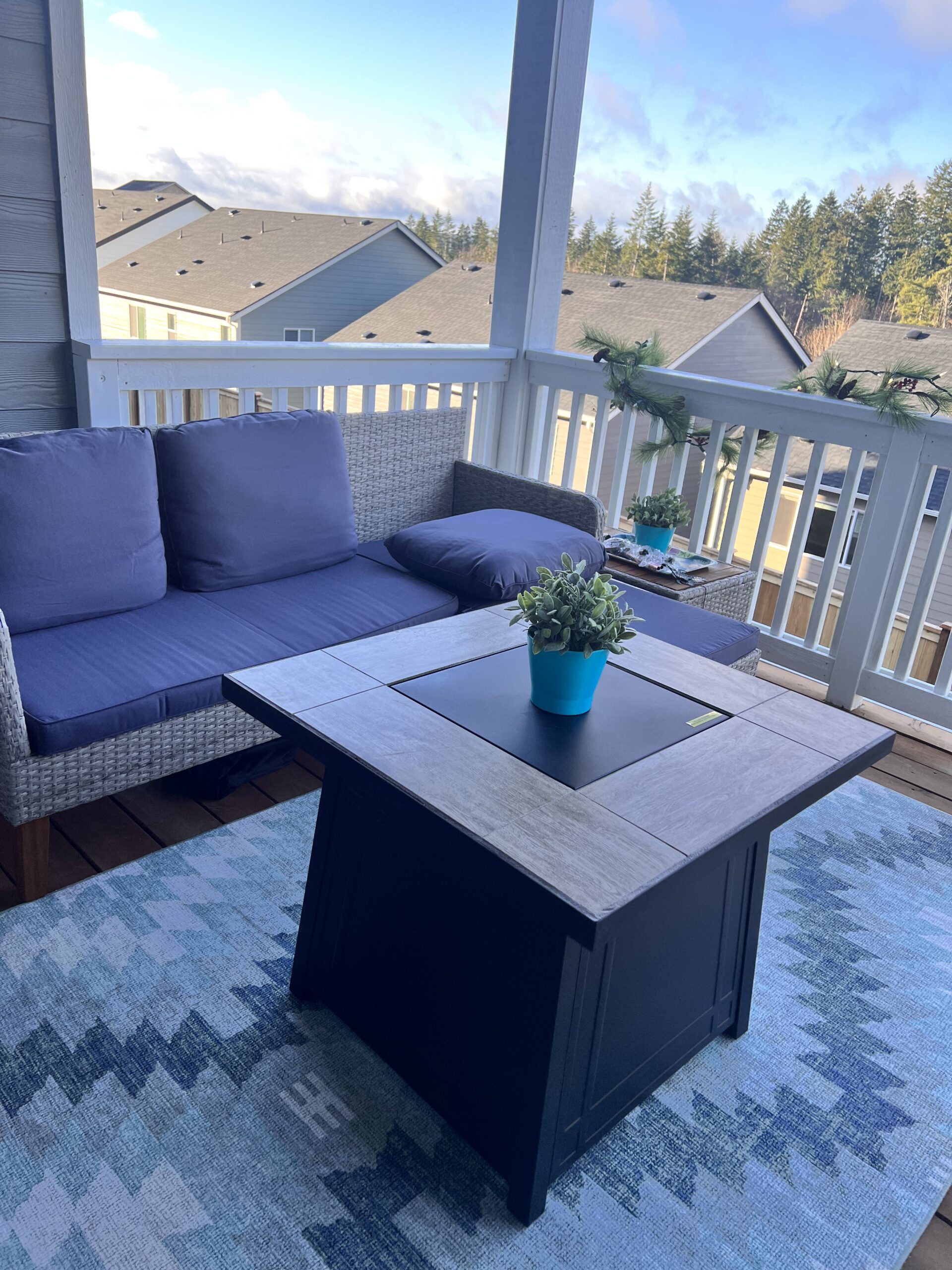 Covered deck with fire pit table and seating overlooking treed view at 962 Thrush Ct SE, Port Orchard